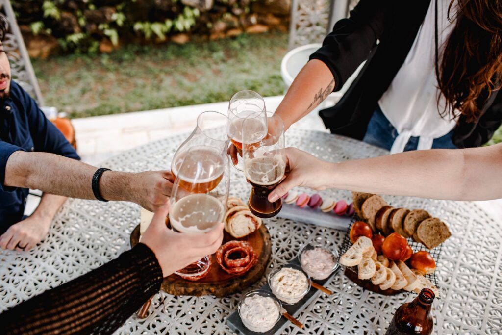 Friends enjoying a toast with beer and snacks during an outdoor gathering, featuring a joyful celebration atmosphere.
